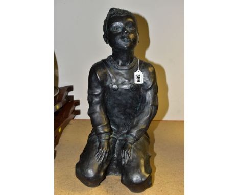 A CONTEMPORARY BRONZED CERAMIC SCULPTURE OF A GIRL KNEELING, wearing dungarees and her hair in a bun, incised P J to the sole