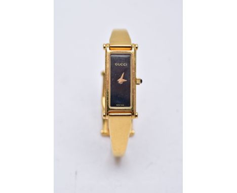 A LADIES GUCCI 1500L WRISTWATCH, the yellow metal wristwatch designed with a black rectangular dial signed 'Gucci', vacant nu