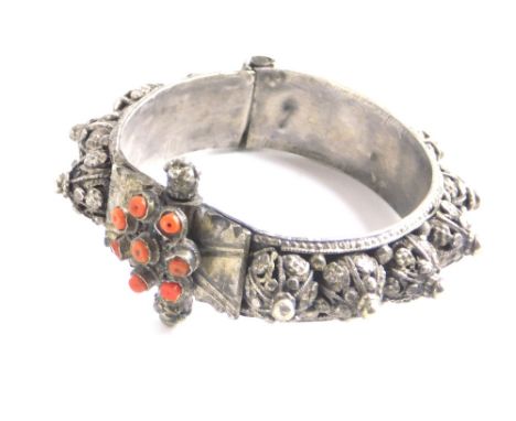 A highly elaborate Middle Eastern bangle, the clasp set with orange stones, the body with raised flower heads and orbs, unmar