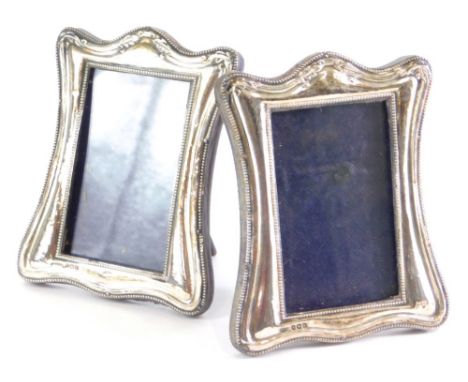 A pair of George V silver photograph frames, each with serpentine tops, raised with flowers with plain easel backs, Birmingha