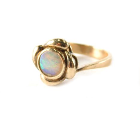 An opal dress ring, with central circular opal in rub over setting, with pleated flower design, yellow metal stamped 9ct, rin