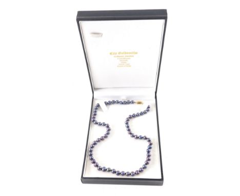 A cultured pearl necklace, with purple beads, on string strand with a yellow metal clasp stamped 9ct, 42cm long overall, boxe