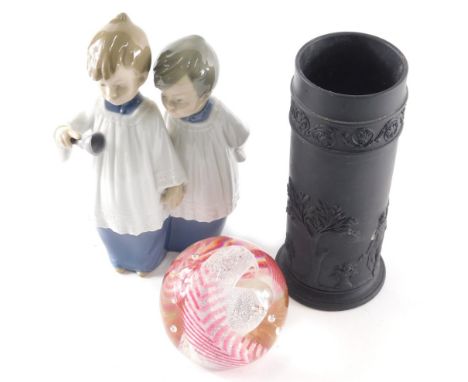 A 20thC Nao figure of two choirboys, 16cm high, a Wedgwood black basalt vase of cylindrical form, and a pink fern paperweight