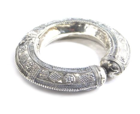 A Middle Eastern C-scroll bangle, elaborately decorated with diamonds and orbs, 12cm wide. 
