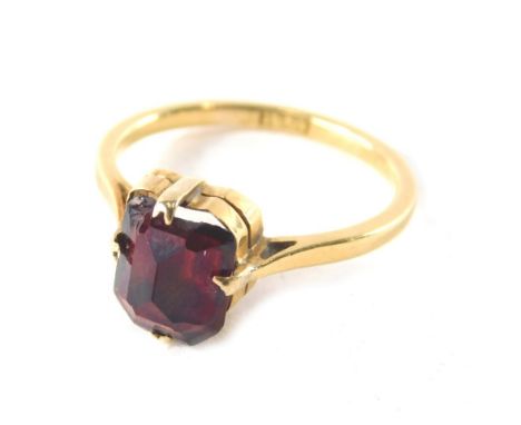 A ruby dress ring, the faceted square cut ruby in four double claw setting on a raised basket with pierced design shoulders, 