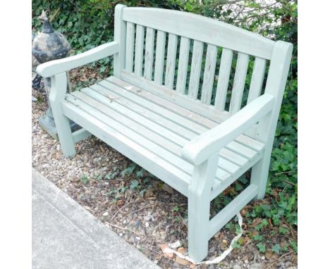 A green painted and slated garden bench, 123cm wide.
