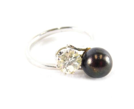 A modern dress ring, set with black and cultured pearl, and paste white stone, with twist design central panel, on white meta