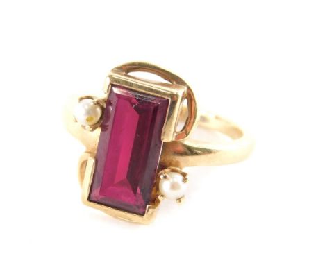 A ruby and seed pearl dress ring, the rectangular cut ruby in rub over setting with two cultured pearl surrounds, on a yellow
