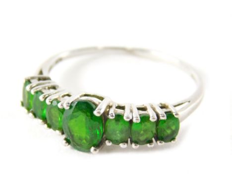A 9ct white gold dress ring, set with seven pale green stones, on a raised basket, ring size R½, 2.3g all in.