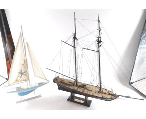A painted model of a ship, with realistic rigging and deck, and a further painted yacht on wooden stand, 59cm high. 