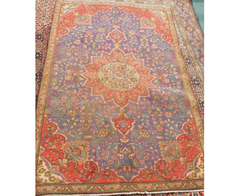 A vintage Persian Tabriz carpet, with central flower shaped medallion in red, on a blue ground with one narrow border, 290cm 