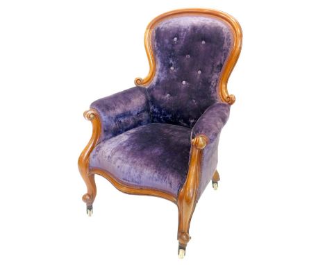 A Victorian mahogany show frame armchair, upholstered in buttoned purple velvet, on scroll carved supports with ceramic casto
