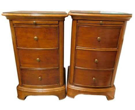 A pair of Laura Ashley hardwood bedside cabinets, each of bowfronted form, with a slide and three drawers, with turned brass 