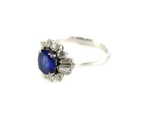 An 18ct white gold sapphire and diamond cluster ring, with oval cut dark blue sapphire, 7.4mm x 6.8mm x 3mm, surrounded by ei