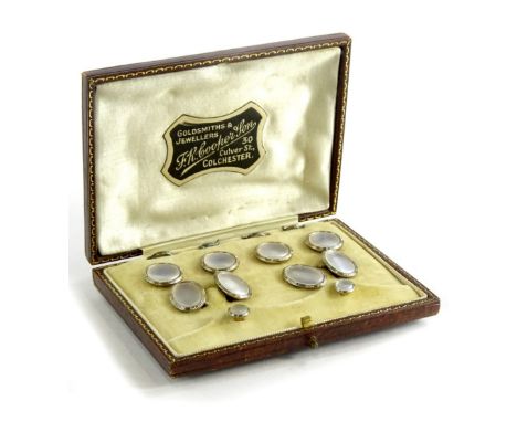 A gentleman's collar tie and cufflinks set, each set with mother of pearl panel, surrounded by white metal border, on yellow 