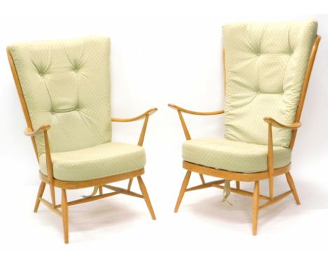 A pair of Ercol type cottage winged armchairs, with pale beech frames on turned tapering legs. The upholstery in this lot doe