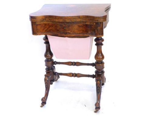A Victorian walnut games/worktable, with the shaped top hinged to reveal chess, back gammon and cribbage boards of a frieze d