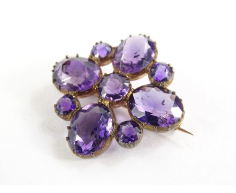An amethyst set decorative brooch, with floral leaf design, flanked by two smaller stones, in a gold plated frame, 2.5cm wide