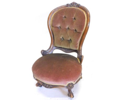 A walnut spoonback nursing chair, the frame carved with scrolls, leaves etc., upholstered in buttoned maroon coloured velvet,
