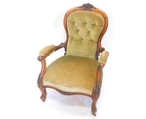 A Victorian walnut showframe armchair, upholstered in buttoned green dralon, the frame carved with scrolls etc. on cabriole l