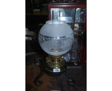 A brass Oil lamp on wrought iron base with raised floral design shade.