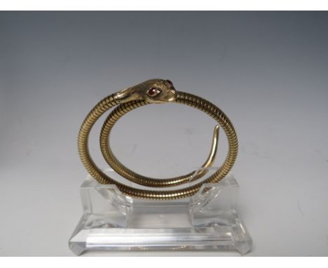 A HALLMARKED YELLOW &amp; SPRUNG METAL SNAKE ARM BANGLE. with inset garnet / ruby eyes, indistinct hallmarks - possibly 375, 