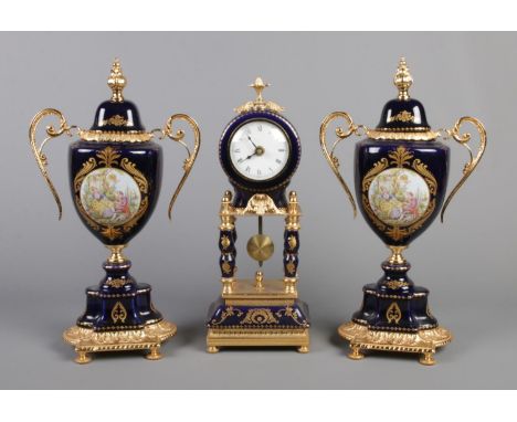 A gilt metal and ceramic three piece clock garniture, with Roman Numeral face and central piece flanked by two lidded urns, e