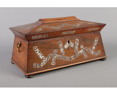 A Victorian tea caddy of sarcophagus form, having mother of pearl inlay and brass loop handles.  Missing parts of inlaid deco