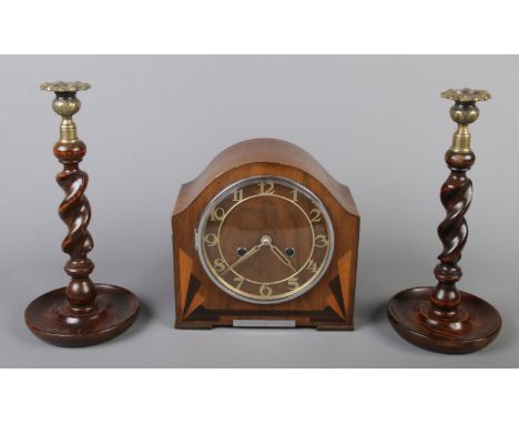 An Art Deco walnut mantel clock with inlaid decoration along with a pair oak barley twist candlesticks.  
