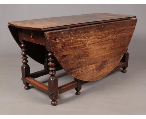 A period oak gate leg dining table with single drawer to one end raised on bobbin turned legs and bun feet. Height 73cm, Exte