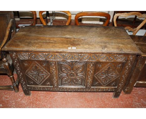 A late 17th Century oak coffer, with a hinged lid, the central panel with stylized floral decoration flanked by panels carved