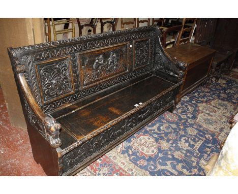 A 19th Century carved oak hall seat, the central panel depicting a tavern scene, with a hinged lid seat 156cm length