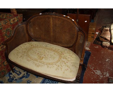 An early 20th century Louis XVI style carved walnut 'bergere' canape with loose needlepoint cushion cushion.120cm wide.