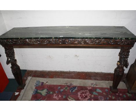 An oak carved console with simulated green marble top, trailing foliage frieze, supported on caryatids 86cm high, 154cm wide