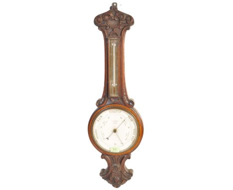 A 19th Century Victorian oak framed aneroid banjo barometer having floral carving to the top above a thermometer and a white 