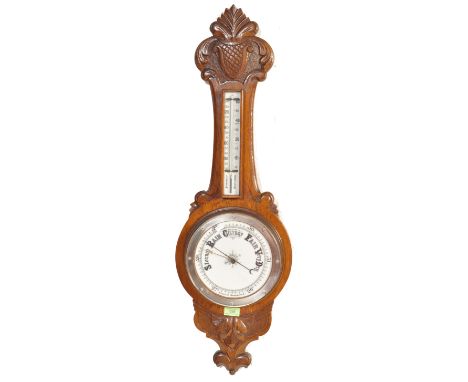 An early 20th century circa 1920s oak aneroid barometer of banjo form a milk glass facia behind bevelled glass with thermomet