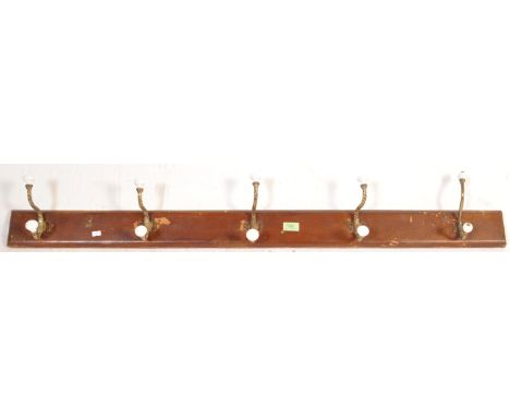 A late 19th century Victorian wooden hat / coat rack. The wall hanging rack having brass barley twisted hooks with white cera