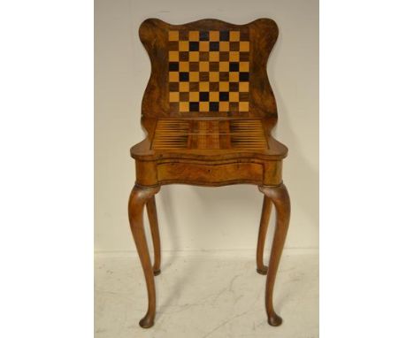 An early 20th century Queen Anne style walnut fold over games table with chequer board, cribbage board, and backgammon board,