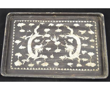 A Chinese papier mache rectangular tray with inlaid mother of pearl decoration depicting dragons chasing flaming pearl - 50x3