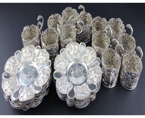 A set of twelve Iranian white metal cups and saucers, the cups having pierced side, chased and engraved with vine leaves and 