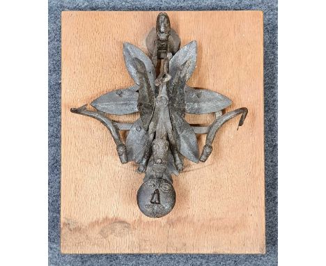 An antique wrought iron door knocker, in the form a dragon flanked by sea serpents, later mounted on an oak panel, 38 x 32cm