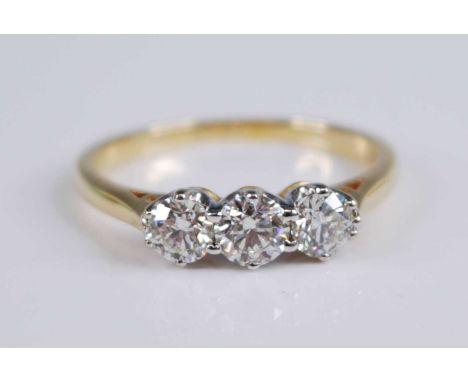 An 18ct yellow and white gold diamond three stone ring, featuring three graduated round brilliant cut diamonds in claw settin