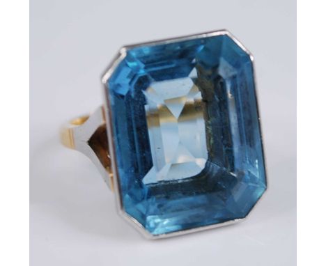 A yellow and white metal aquamarine single stone ring, featuring an emerald cut aquamarine in a bezel setting with bifurcated