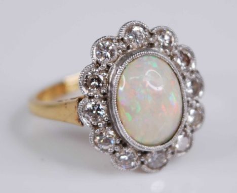 An 18ct gold and platinum, opal and diamond set cluster ring, arranged as a central opal cabochon measuring approx 9.5 x 8mm,