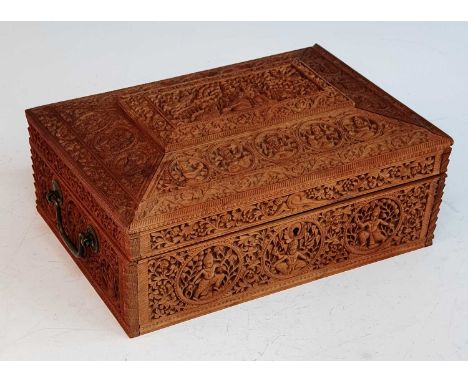 A 19th century Anglo-Indian sandalwood box, profusely carved with figures amongst foliage, the lid lifting to reveal a mirror