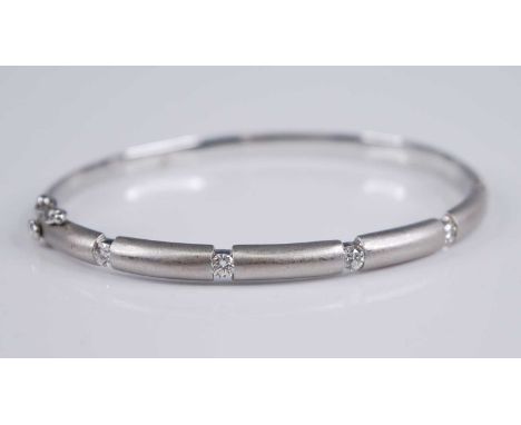A contemporary 18ct white gold and diamond set hinged bangle, half with six finely brushed gold sections dispersed with a sin