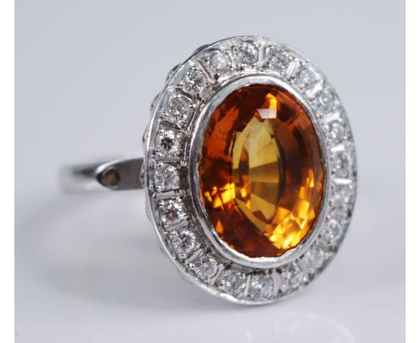 A platinum citrine and diamond oval cluster ring, comprising a centre oval faceted citrine within a border of 20 round brilli