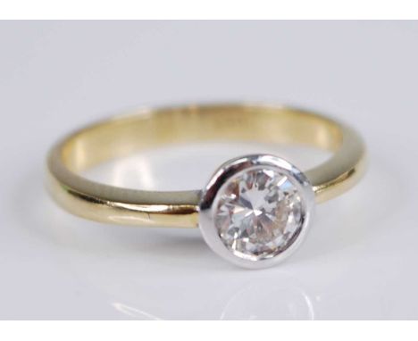 A yellow and white metal diamond solitaire ring, featuring a round brilliant cut diamond in a bezel setting, diamond dimensio