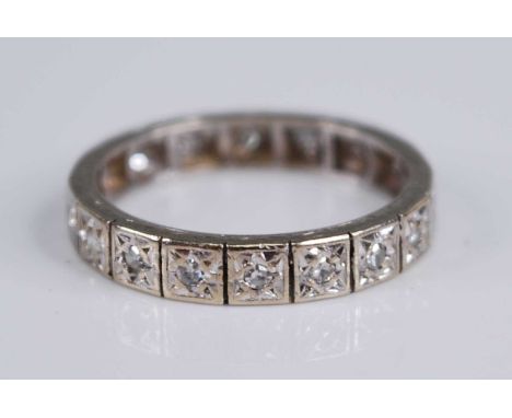 A white metal diamond set eternity ring, arranged as 20 round cuts in carved star settings, total diamond weight estimated as