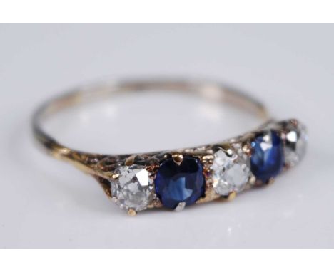 A yellow metal, sapphire and diamond half hoop eternity ring, featuring two oval faceted sapphires and three graduated Old Eu
